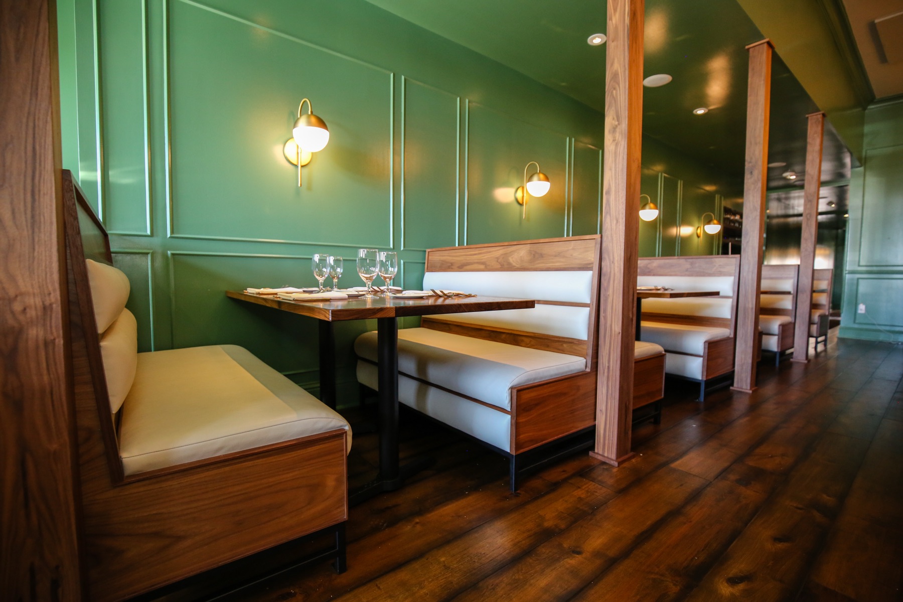Walnut banquettes against green paneled walls