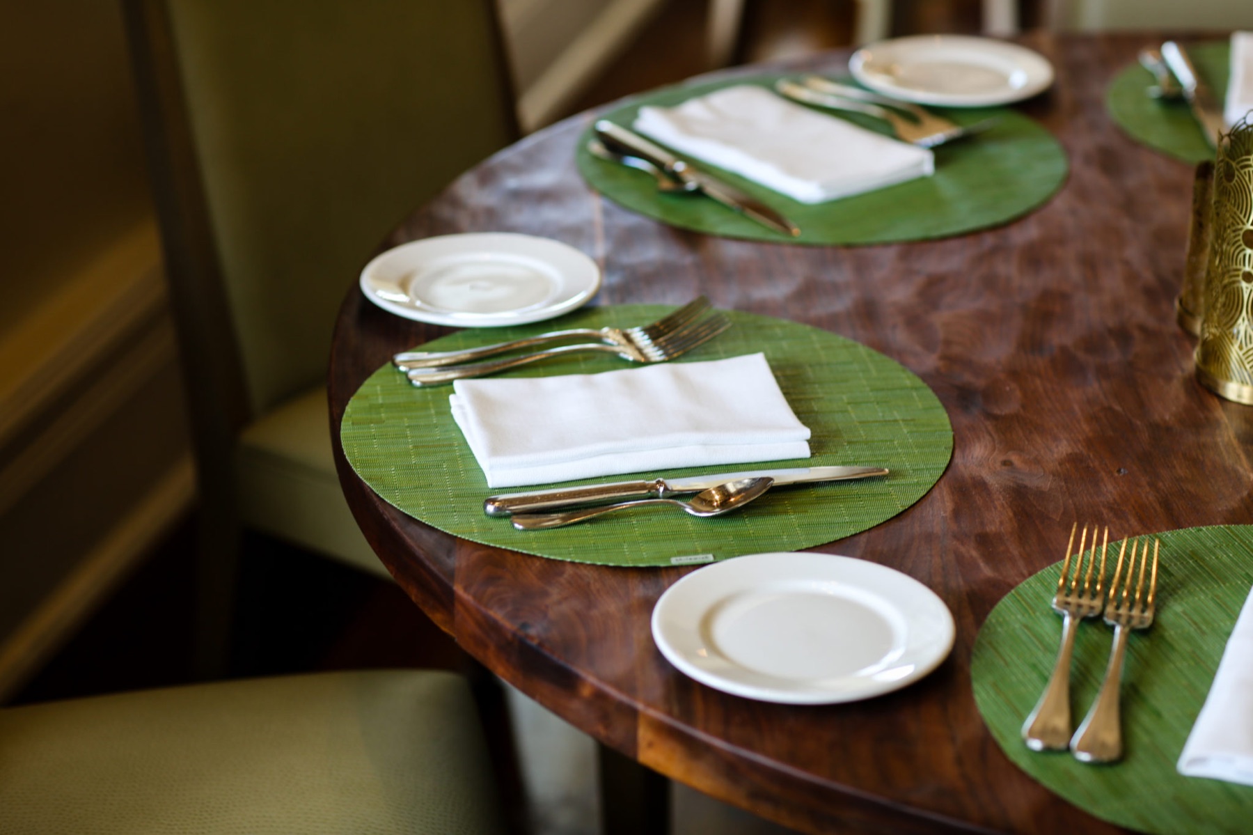 Round walnut dining table set with green chargers