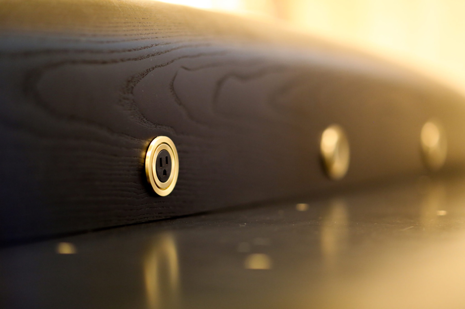 Brass-ringed power outlet set into a black ash surface