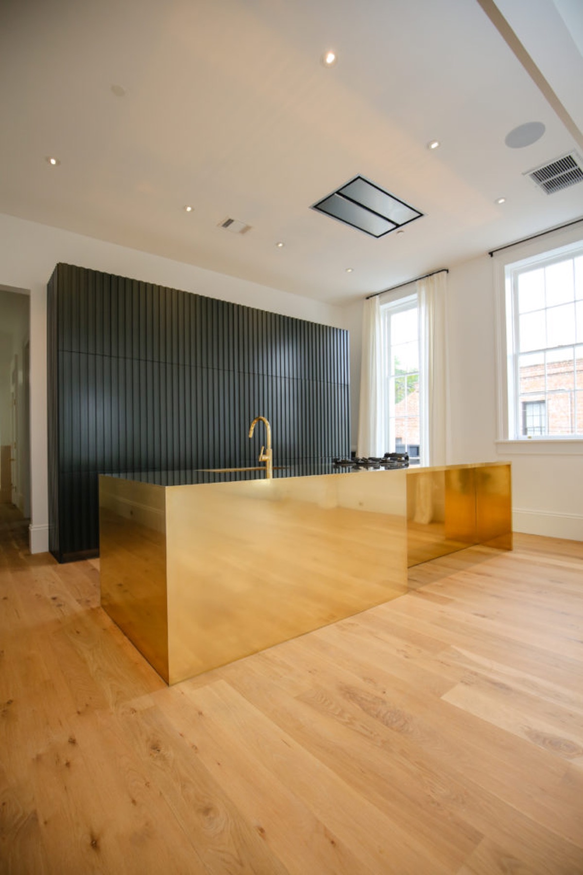 Brass-clad kitchen island in front of a fluted black wall