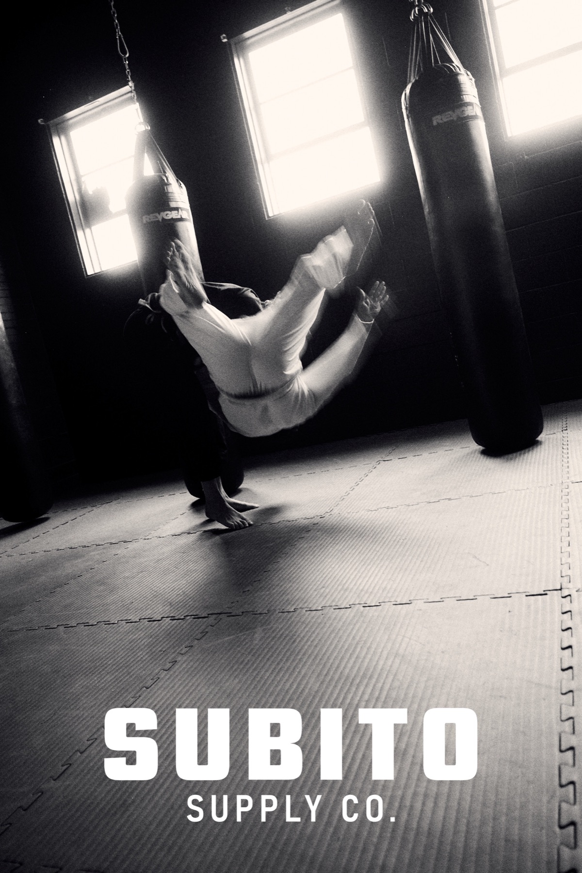 Black and white action shot, athlete inverted in the gym